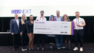 A group of design professionals stand on KBIS NEXTStage to award the Grand Prize winner of the Kickstarter Zone with a giant $5,000 check.